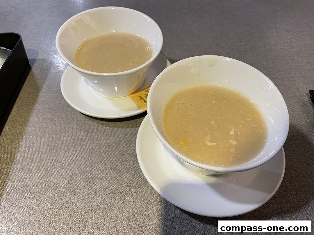 Two bowls of creamy corn soup with visible corn kernels and shredded chicken.