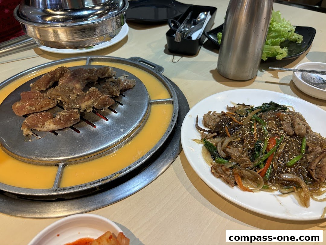 A table setting with Korean street food, including grilled meat and Japchae.