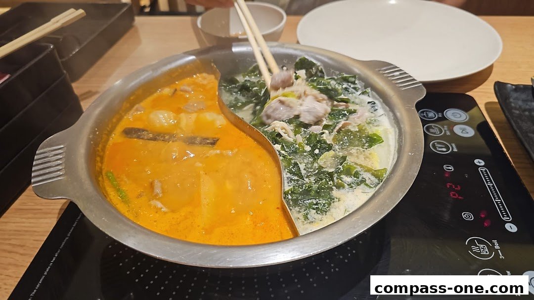 A split pot of shabu-shabu with two different broths and various ingredients.