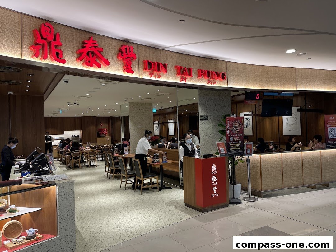 The entrance and dining area of Din Tai Fung restaurant, with staff and customers visible.