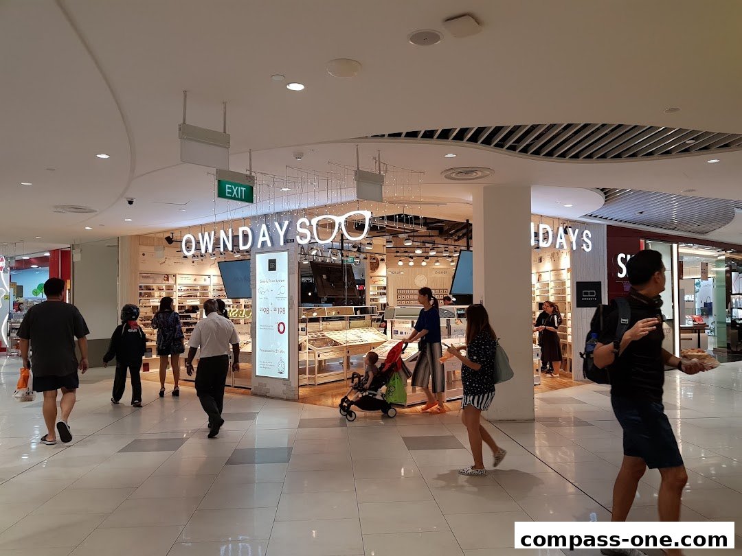 People walking past the OWNDAYS optical shop in a mall.