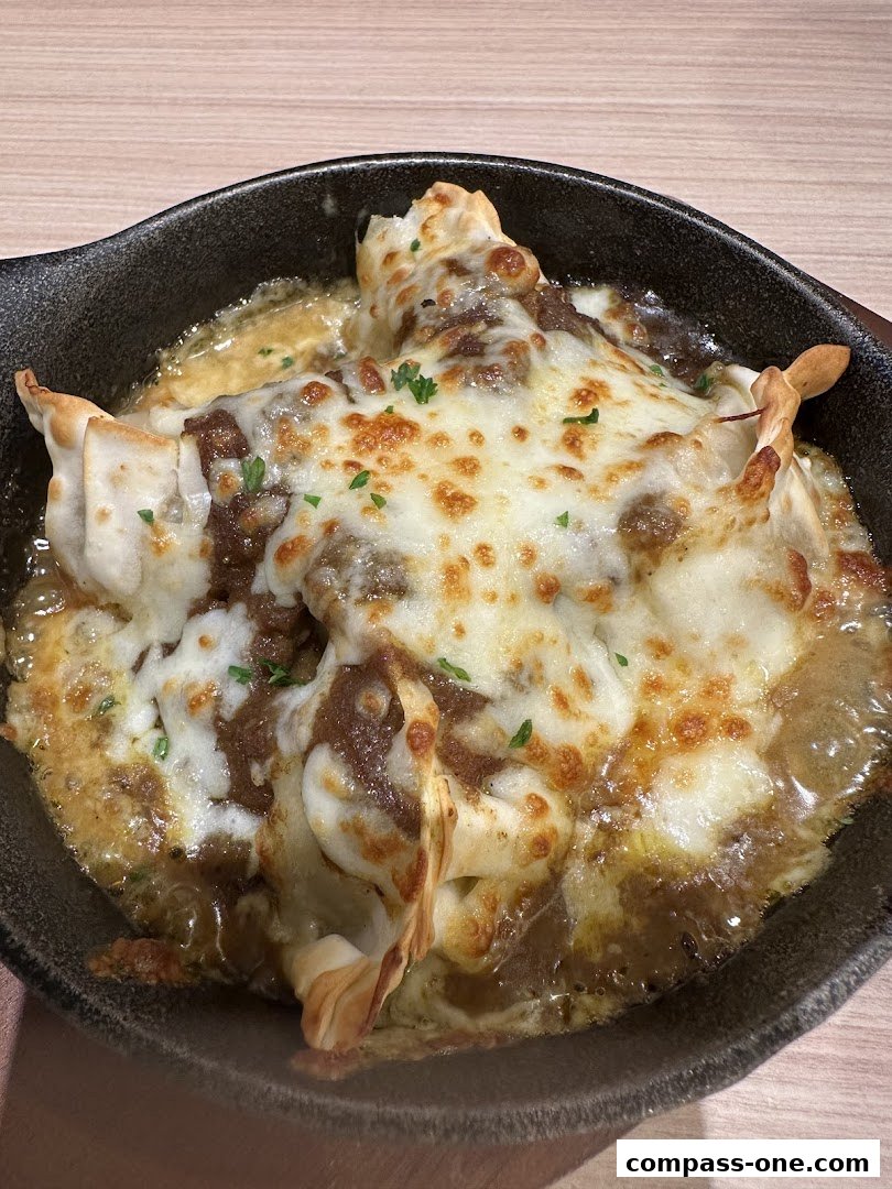 A close-up of a dish with dumplings covered in melted cheese and sauce.