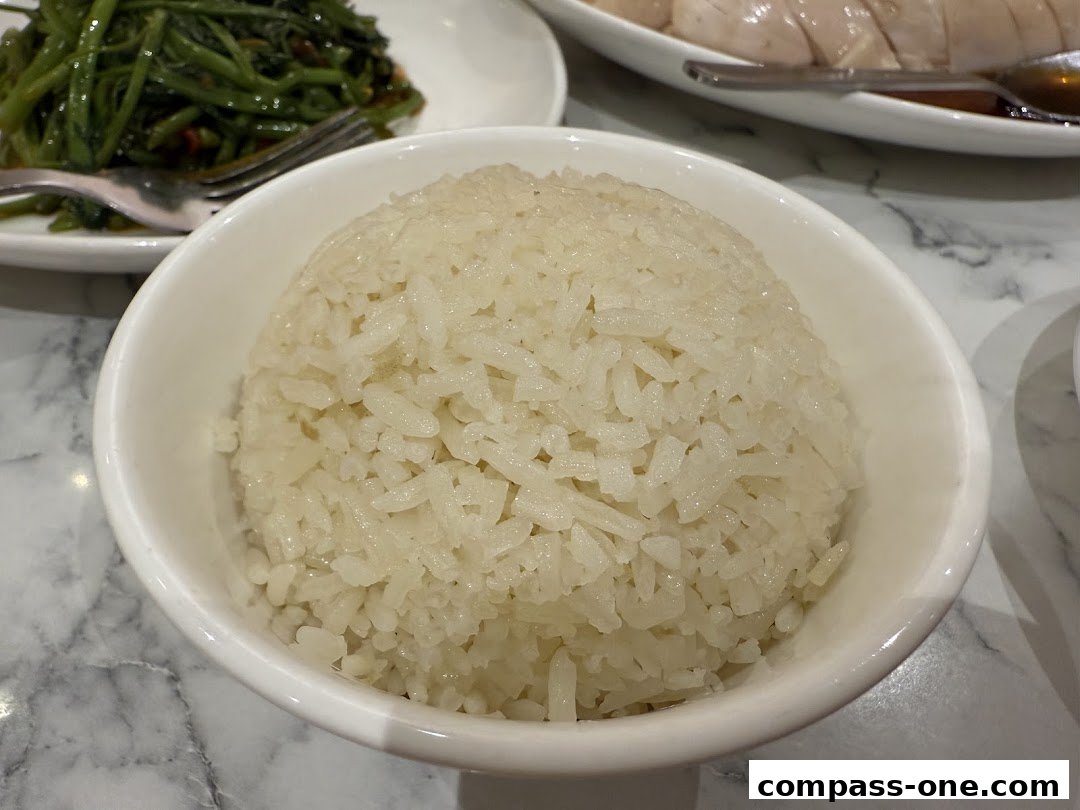 A close-up of a bowl of fluffy white rice, with a side of stir-fried vegetables and chicken in the background.