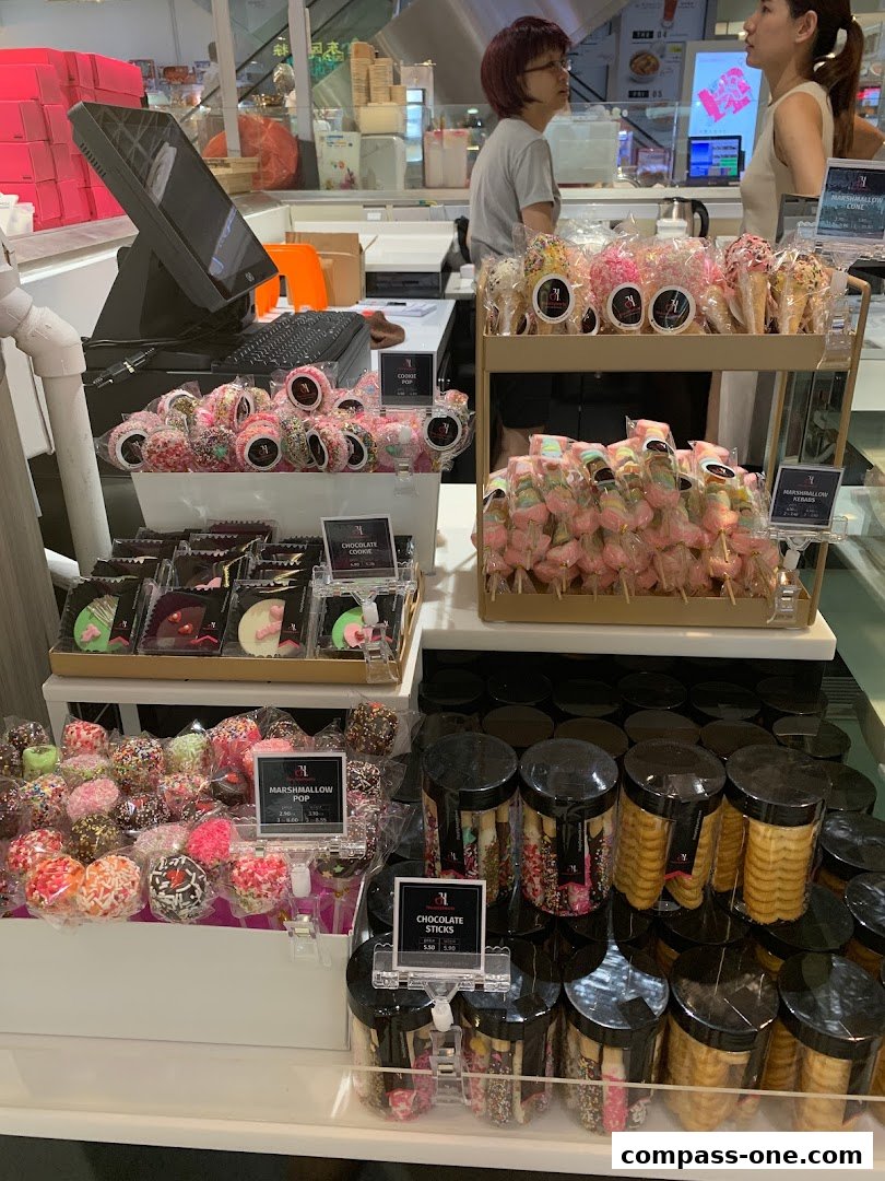 A display of colorful sweets including cookie pops, marshmallow skewers, and chocolate sticks.