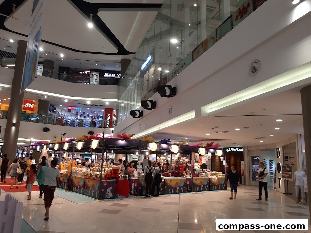 A busy shopping mall interior with various shops and shoppers.
