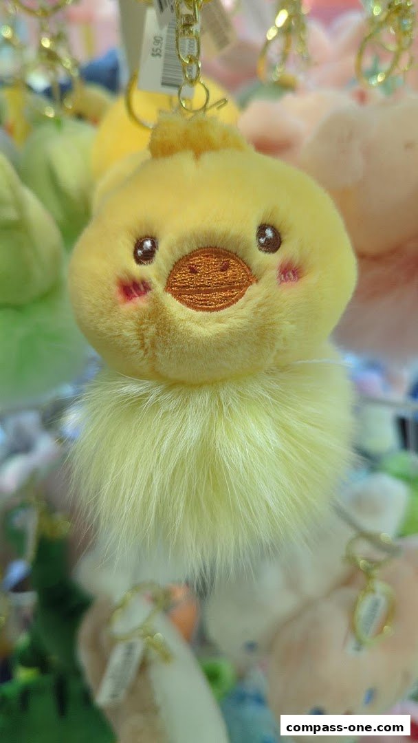 A close-up of a fluffy yellow chick keychain with a price tag.