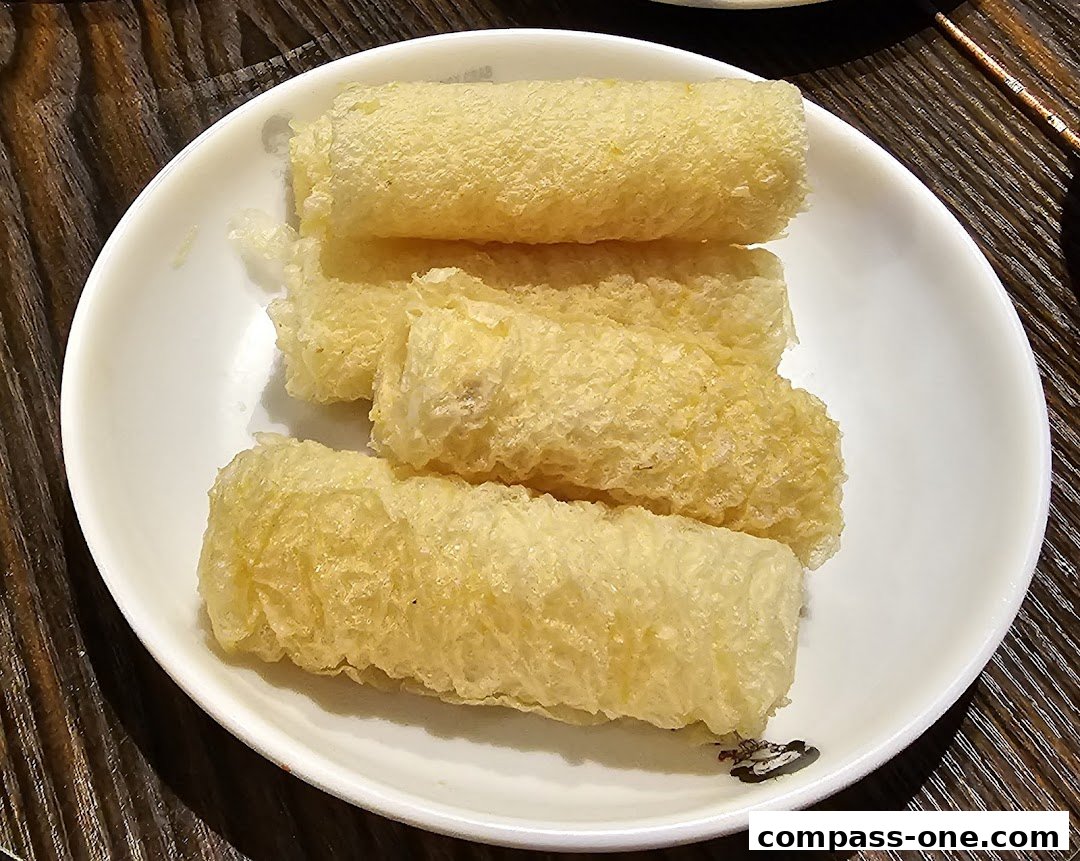 A white plate filled with golden-brown, crispy fried rolls on a wooden table.