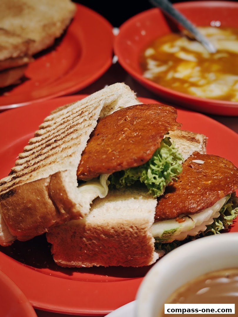 A close-up shot of a delicious kaya toast sandwich with lettuce and cucumber on a red plate.