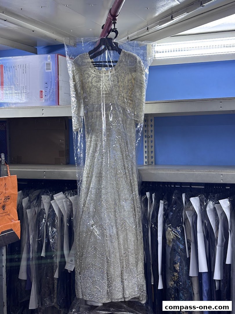 A sparkling white dress is displayed in a plastic bag, ready for dry cleaning.