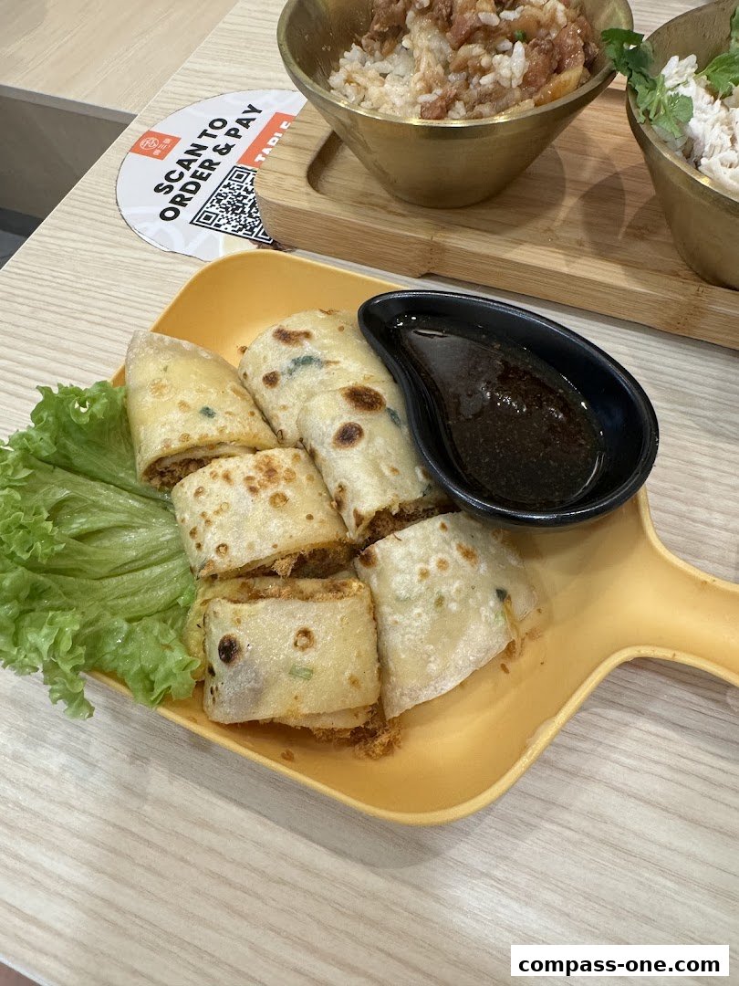 A plate of sliced spring rolls with lettuce and dipping sauce, next to bowls of rice.
