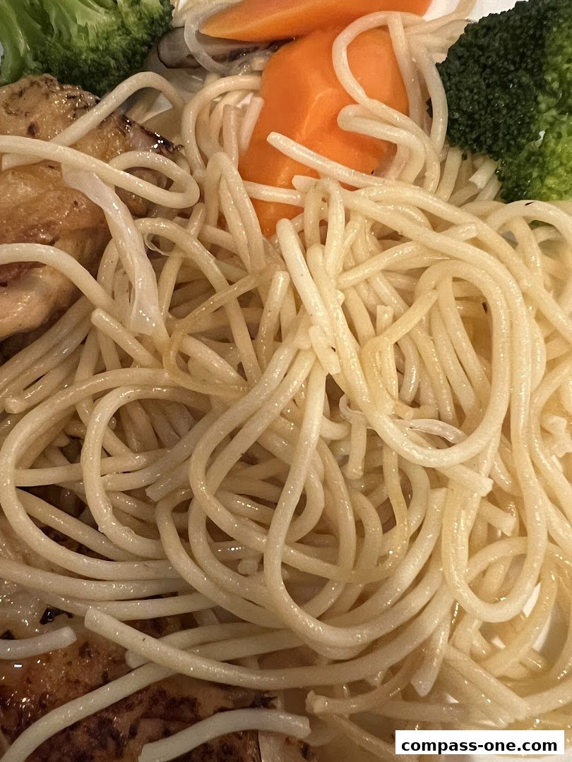 A close-up of a delicious pasta dish with chicken, broccoli, and carrots.