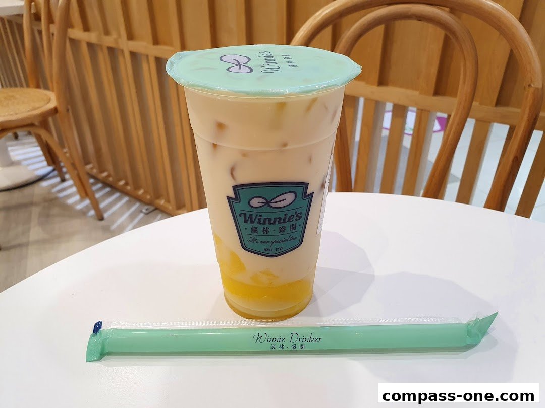 A cup of bubble tea with mango chunks and a straw on a white table.