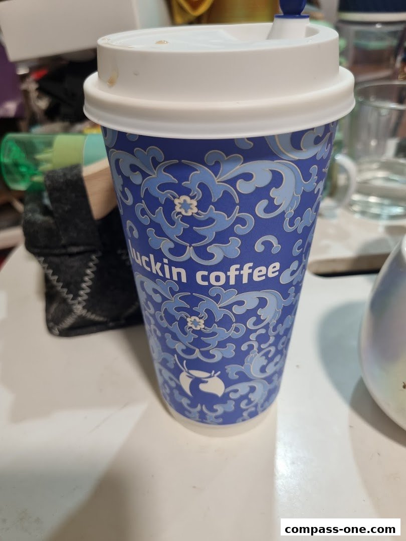 A blue Luckin Coffee cup with a white lid and straw sits on a white surface.