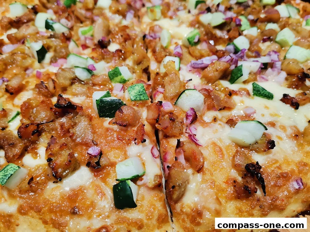 A close-up shot of a delicious pizza topped with chicken, cucumber, and red onions.