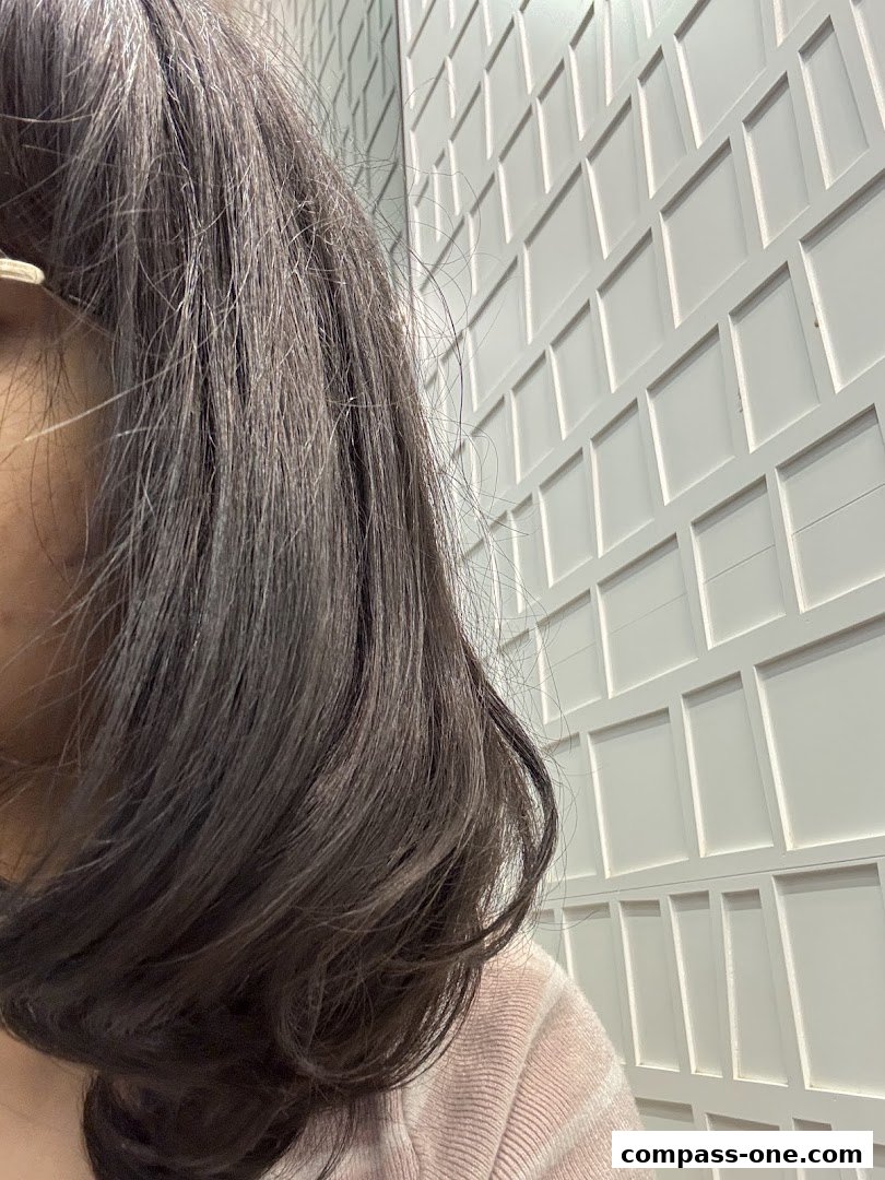 A close-up of a person's dark hair against a white textured wall.