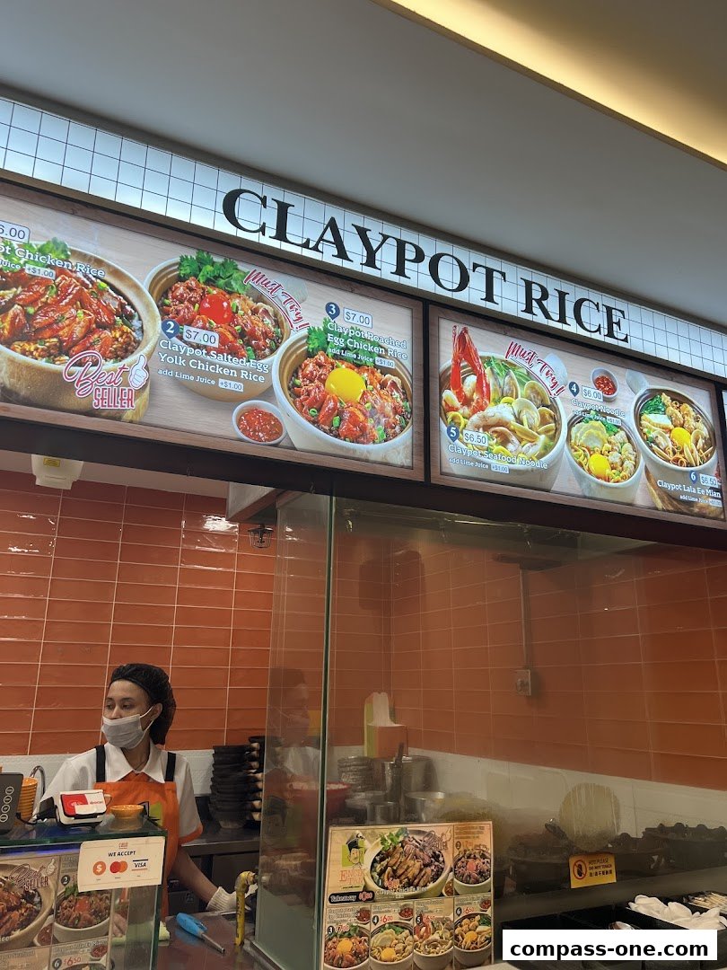A food stall displaying various claypot rice dishes with prices and enticing images.