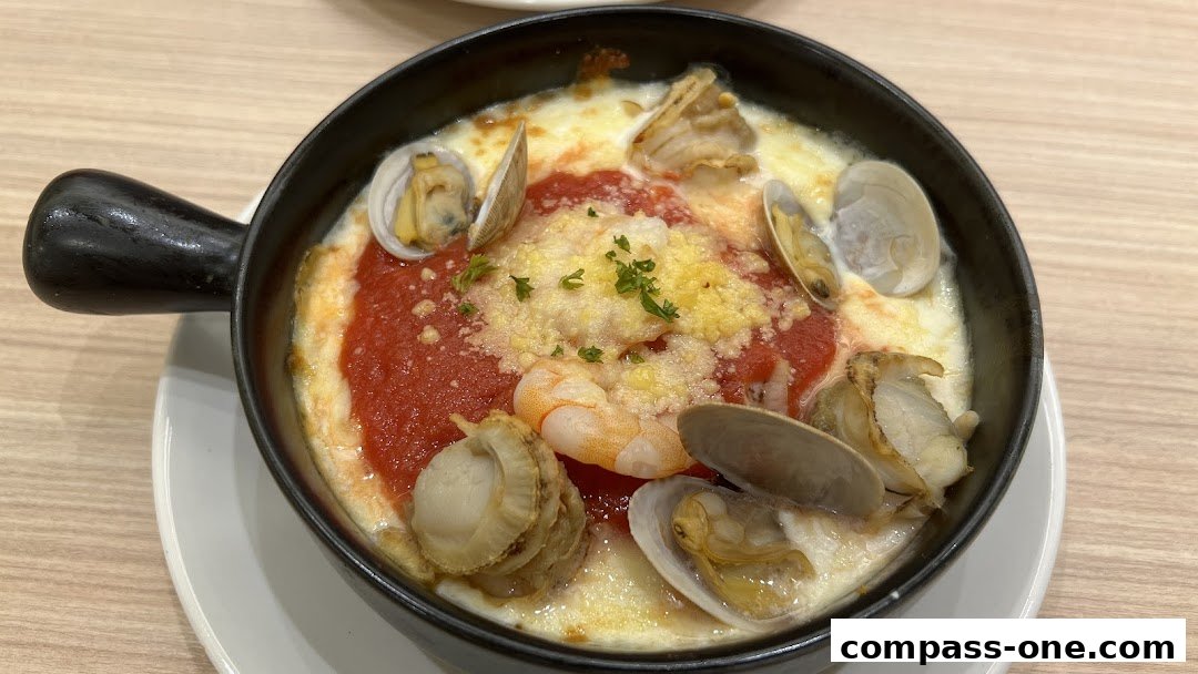 A close-up of a baked seafood dish with clams, shrimp, and tomato sauce topped with cheese.