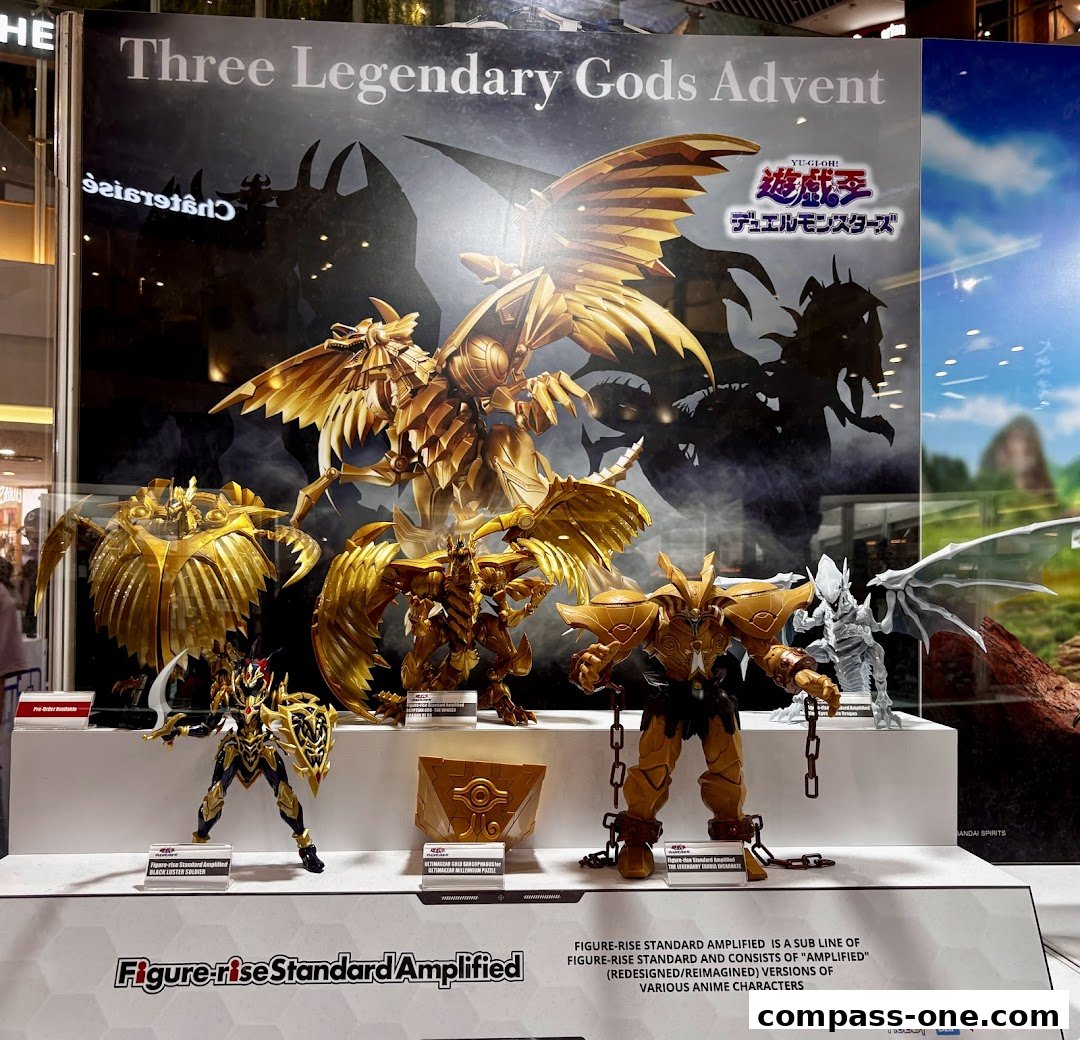 Display of golden anime action figures, likely from Yu-Gi-Oh!, with a promotional backdrop.