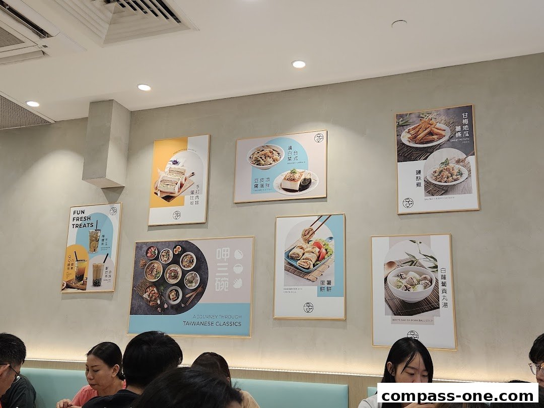 A wall in a restaurant decorated with framed pictures of Taiwanese food and drinks.