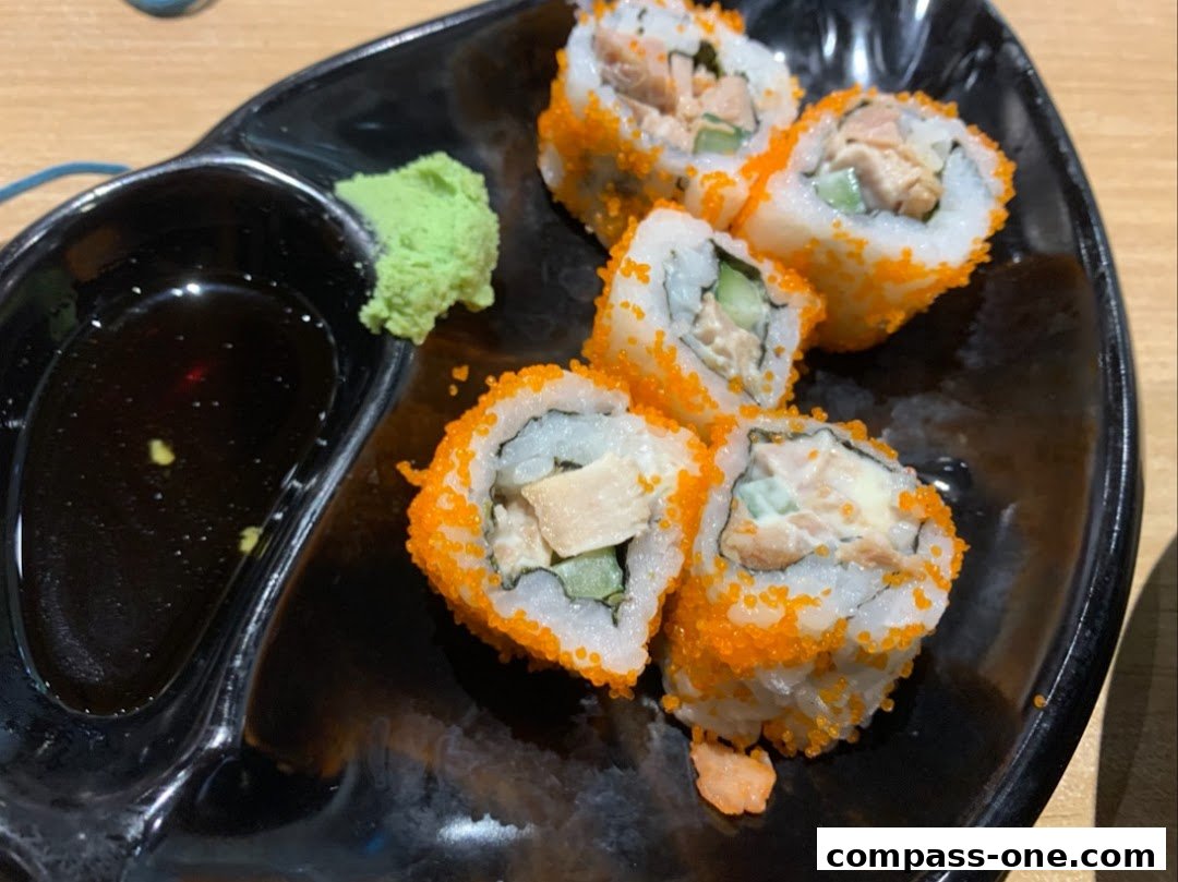 A plate of California rolls with salmon, cucumber, and masago, served with soy sauce and wasabi.