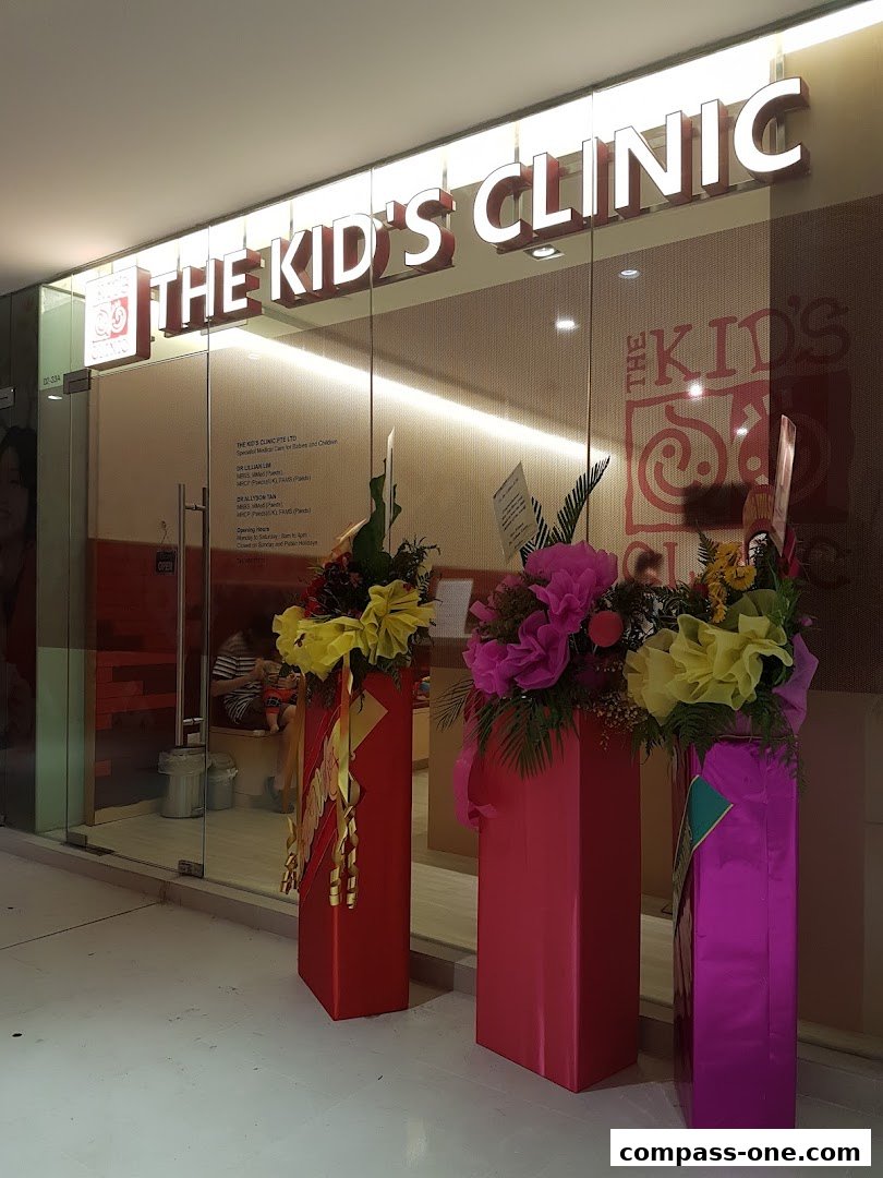The Kids Clinic storefront with illuminated signage and decorative floral arrangements.