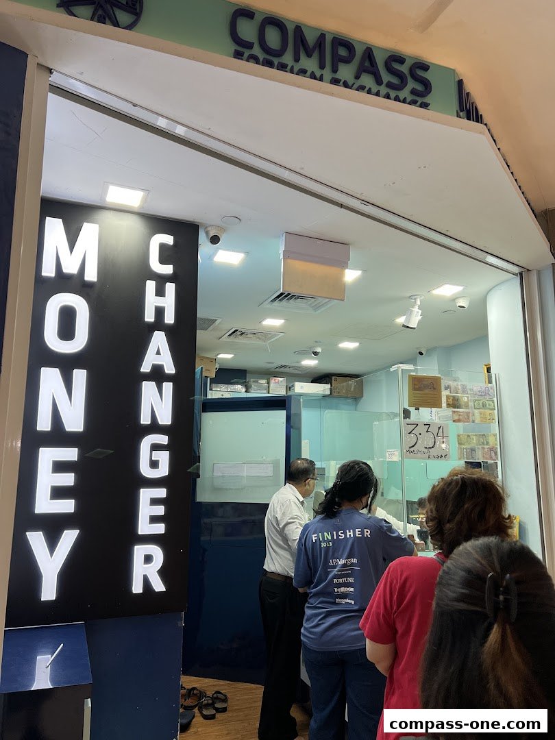 People queuing at a money changer shop with "MONEY CHANGER" signage and foreign currency displayed.
