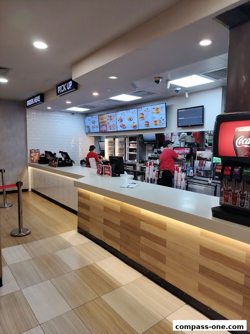 Interior view of a KFC restaurant with staff behind the counter and digital menu boards.