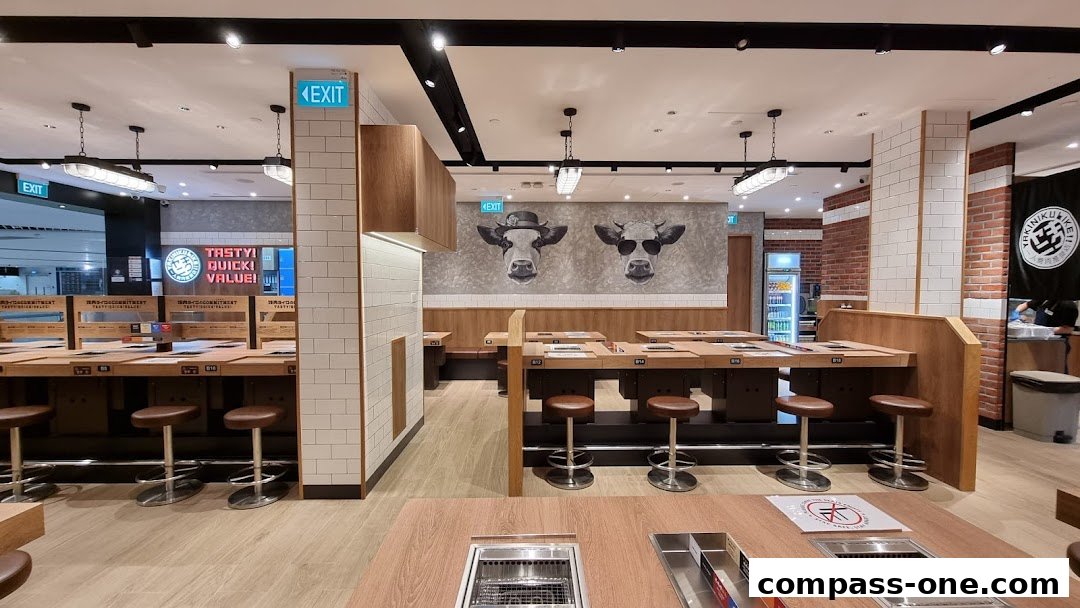 Interior of a Yakiniku Like restaurant with individual grilling stations and cow artwork.