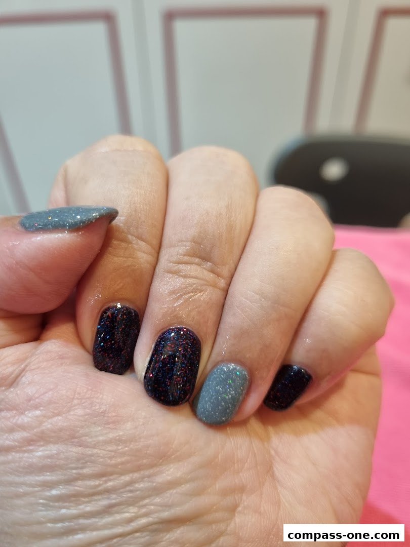 Close-up of a hand with beautifully manicured nails featuring glitter and matte finishes.