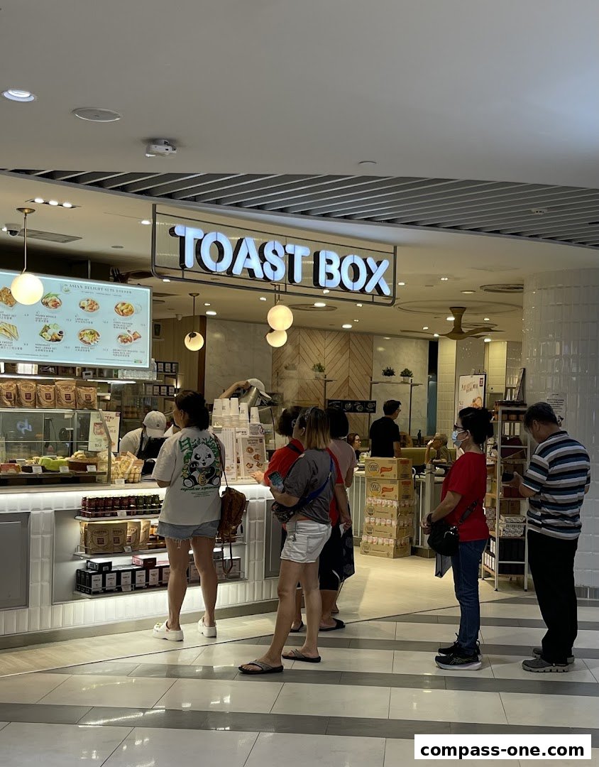 Customers queue at the Toast Box counter, with a menu board displaying food items.