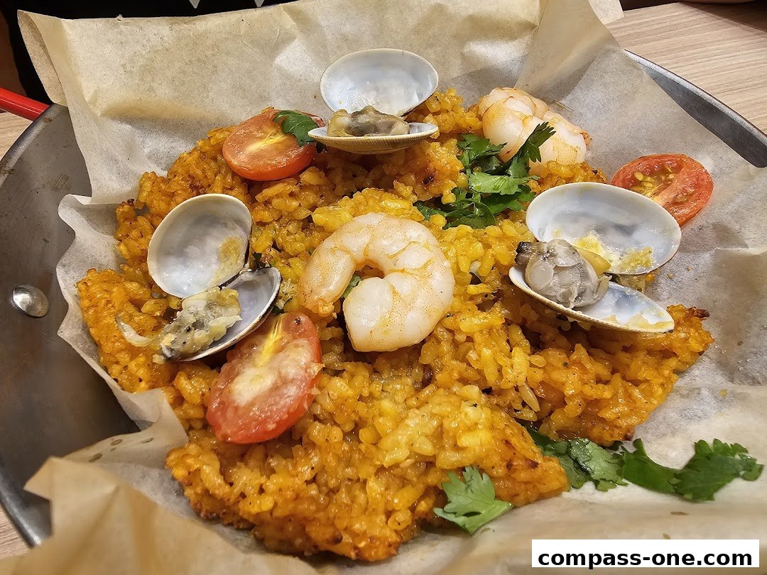 A close-up of a seafood paella dish with shrimp, clams, tomatoes, and cilantro.