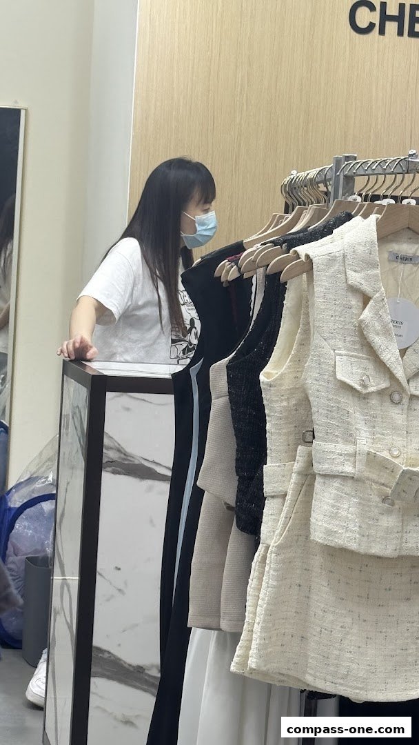 A woman wearing a mask browses through stylish women's clothing at Cheris.