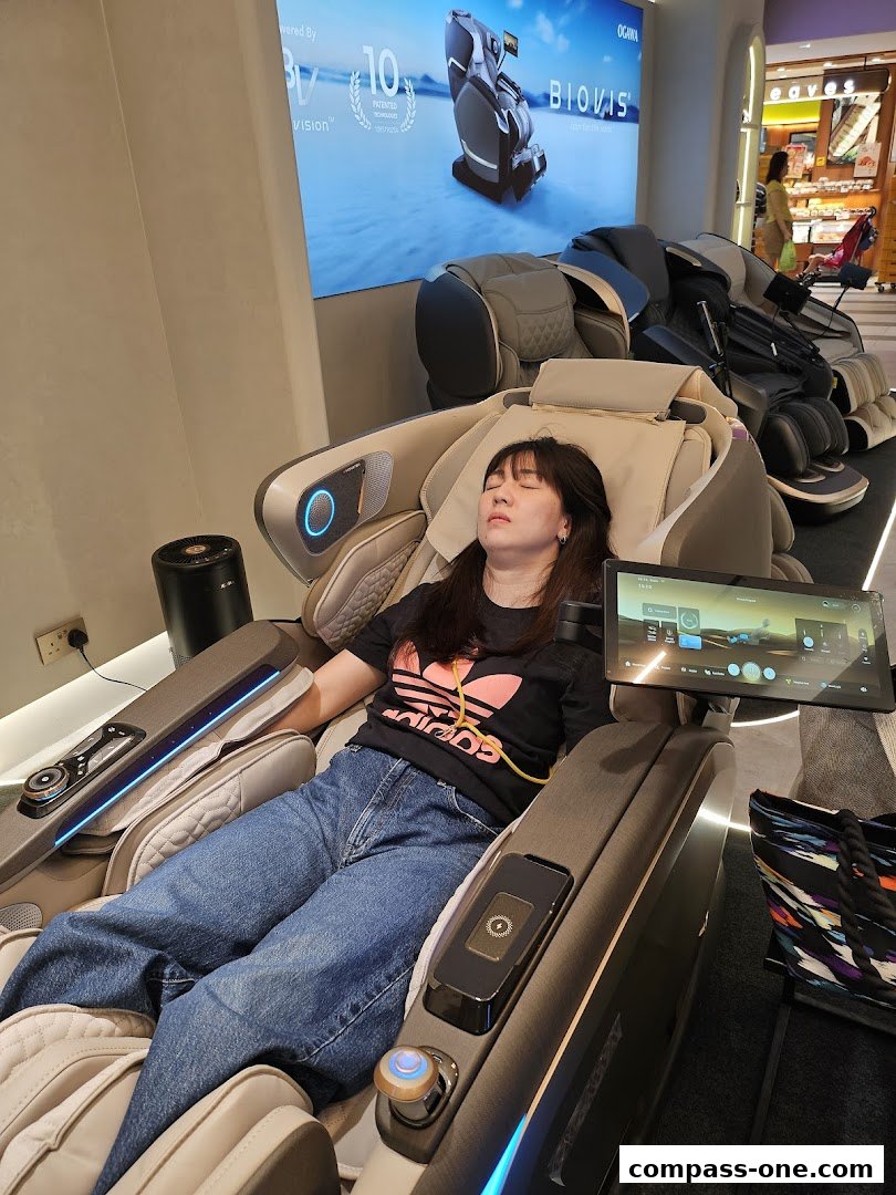 A woman relaxes in a high-tech massage chair with a large screen displaying product information.