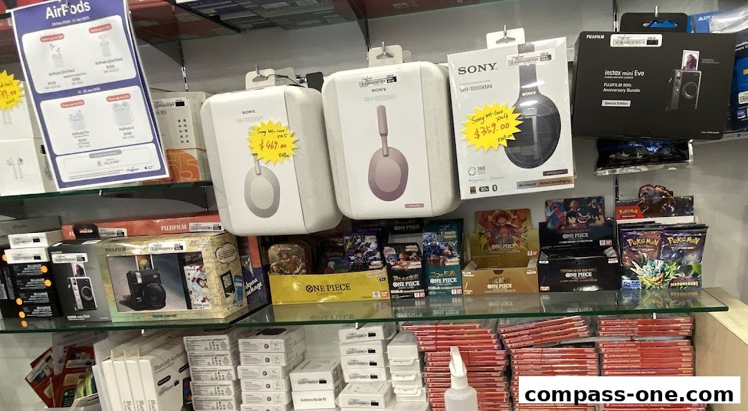 A retail store display featuring headphones, cameras, and collectible card games.