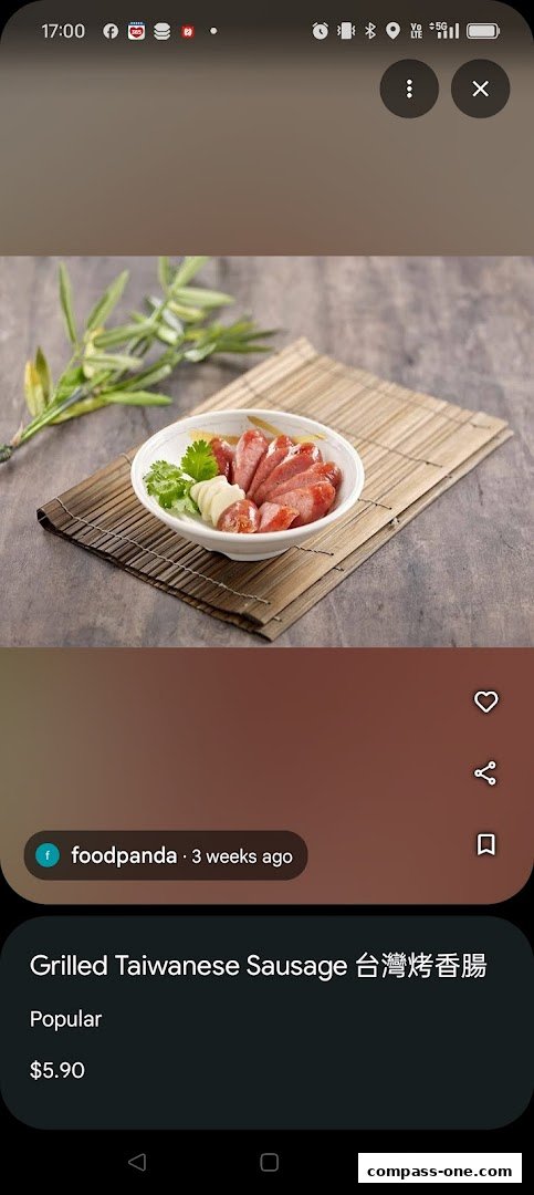 A bowl of sliced grilled Taiwanese sausage with garlic and herbs on a bamboo mat.