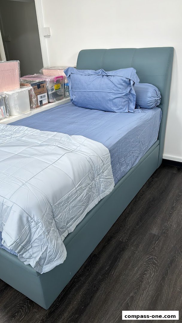 A single bed with blue bedding and a white comforter, in a room with storage boxes.