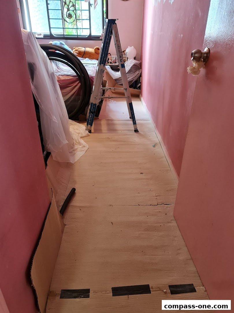 A hallway with pink walls, a ladder, and various items covered in plastic.