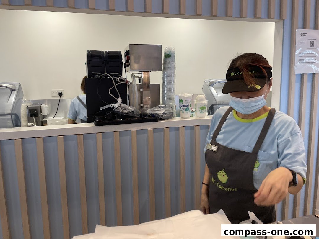 A staff member wearing a mask and apron at the Mr. Coconut counter.