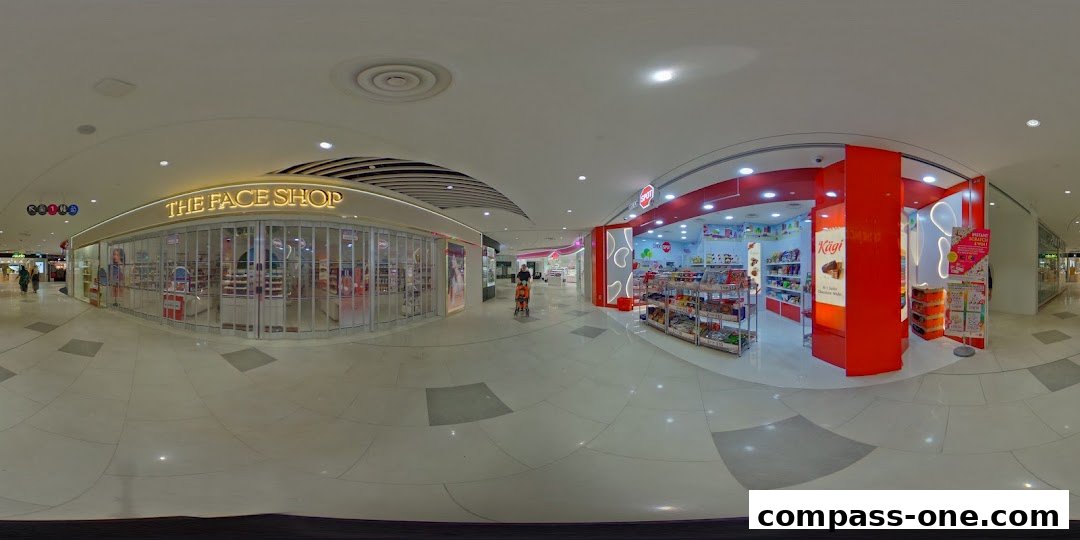 A panoramic view of a shopping mall corridor featuring The Face Shop and a confectionery store.