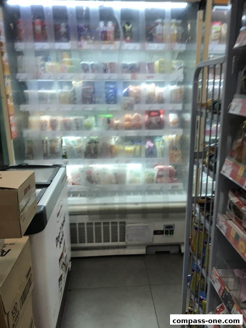 A 7-Eleven store interior with refrigerated display cases filled with drinks and snacks.