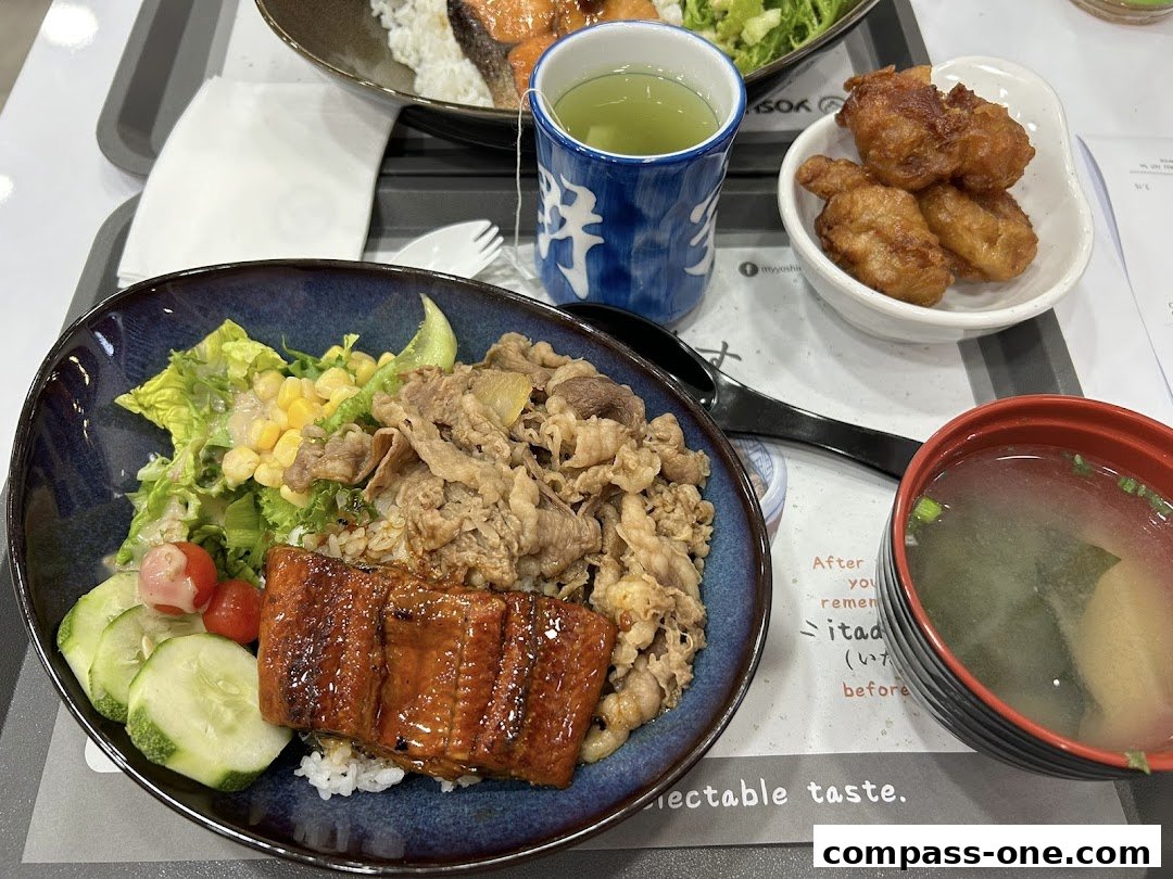 A close-up of a Japanese meal featuring beef and eel over rice, with fried chicken and miso soup.