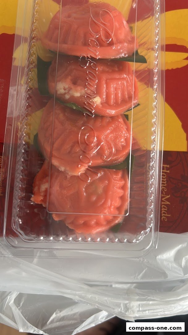 A clear plastic container filled with four red, intricately molded pastries.