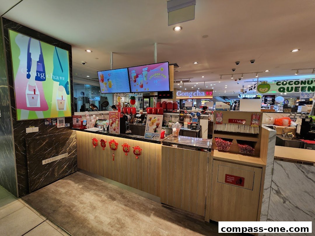 The interior of a Gong Cha bubble tea shop with a counter, menu screens, and seating.