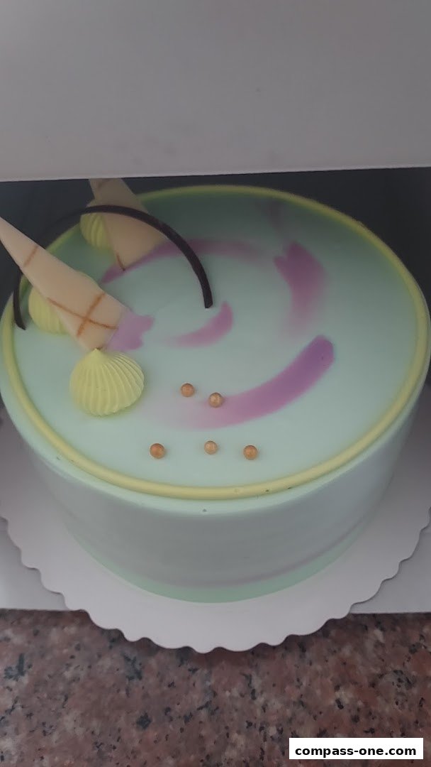 A beautifully decorated round cake with light green frosting and purple swirls.