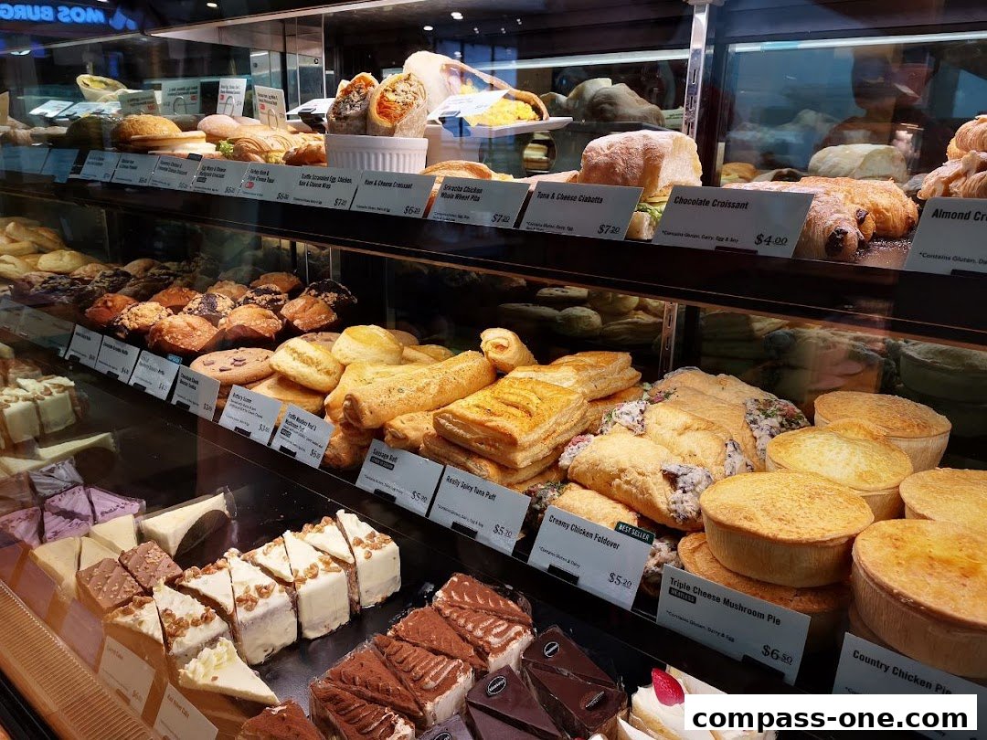 A display case filled with various pastries, pies, and cakes, with price labels visible.