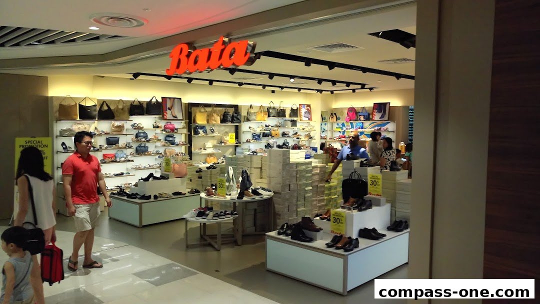 A Bata shoe store interior with displays of shoes and handbags, and customers browsing.