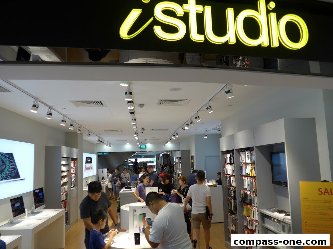 Interior of an iStudio electronics store with customers browsing Apple products.