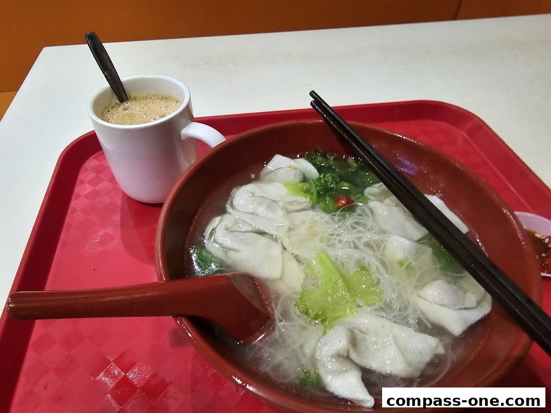 A bowl of wonton noodle soup with a cup of coffee on a red tray.