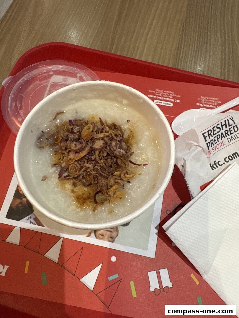 A bowl of congee topped with fried onions on a red tray at KFC.