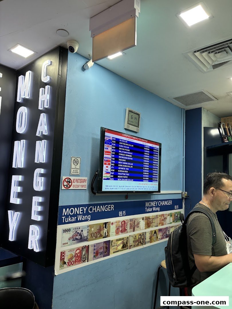 A money changer shop with illuminated signage and a digital display of currency exchange rates.